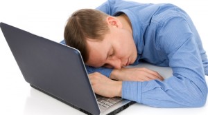 Young man sleeps on a workplace with a laptop computer